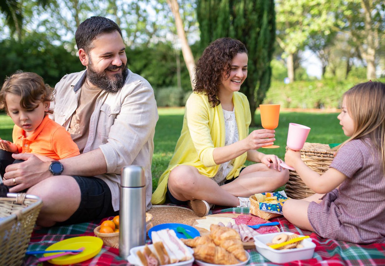 A family gathers for a picnic in the park, sharing food and laughter on a sunny day.