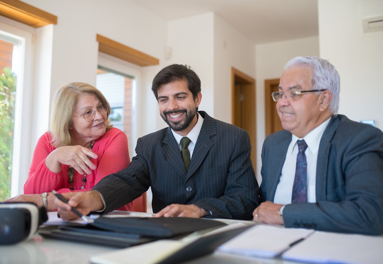Three business professionals seated at a table, collaborating over a laptop during a meeting.